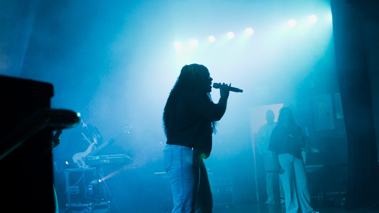 A Champion worship leader singing under blue stage light